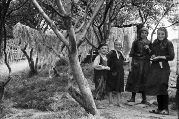 Viaggio in Jugoslavia. Vrhovine: ritratto di gruppo, donne e bambini. Alle loro spalle lana stesa ad asciugare