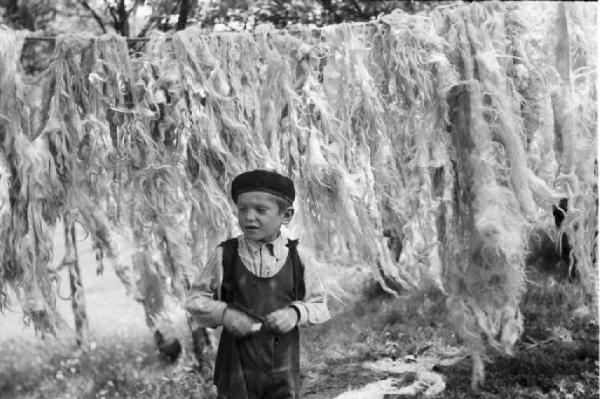 Viaggio in Jugoslavia. Vrhovine. Bambino. Alle spalle lana stesa ad asciugare tra gli alberi