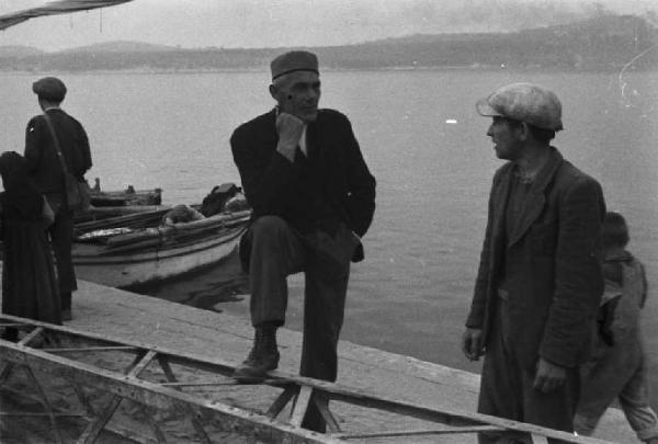 Viaggio in Jugoslavia. Sebenico: gruppo di abitanti discute sul molo, nei pressi di un peschereccio