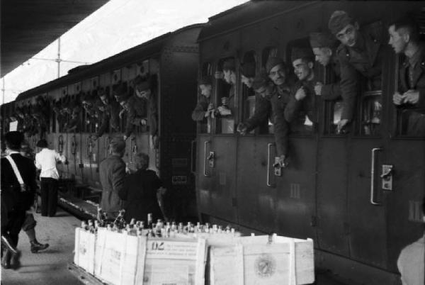 Campagna di Russia. Bolzano - stazione ferroviaria - militari affacciati ai finestrini del treno - casse di bottiglie in banchina
