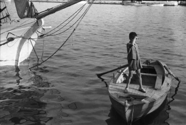 Viaggio in Jugoslavia. Sebenico: fanciullo su peschereccio all'interno del porto