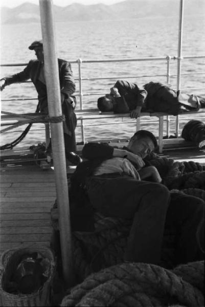 Viaggio in Jugoslavia. Verso Dubrovnik (Ragusa):scorcio del pontile della nave - un uomo osserva un viaggiatore che dorme prono sulla prua dell'imbarcazione