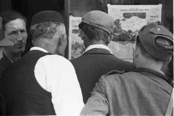 Viaggio in Jugoslavia. Dubrovnik (Ragusa): gruppo di anziani uomini croati discute davanti a un muro su cui rimane appeso un giornale