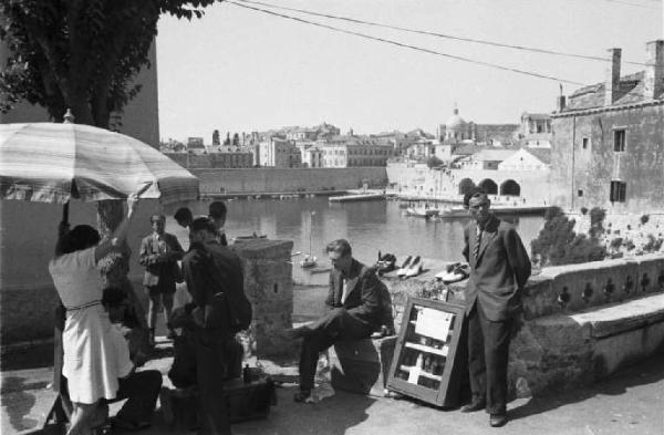Viaggio in Jugoslavia. Dubrovnik (Ragusa): scene di vita quotidiana - gruppo di persone in riva al mare, sullo sfondo la cittÃ 