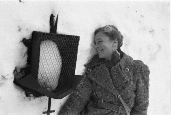 Internamento in Svizzera. Escholzmatt: ritratto femminile, Martina Fischer sdraiata nella neve presso un'edicola votiva lungo la strada delle croci