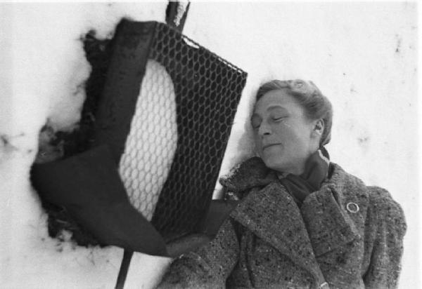 Internamento in Svizzera. Escholzmatt: ritratto femminile, Martina Fischer sdraiata nella neve presso un'edicola votiva lungo la strada delle croci