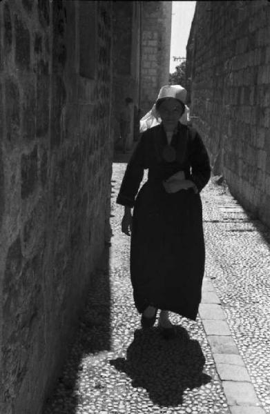 Viaggio in Jugoslavia. Dubrovnik (Ragusa): scene di vita quotidiana - donna in abiti locali cammina lungo il vicolo della cittadina