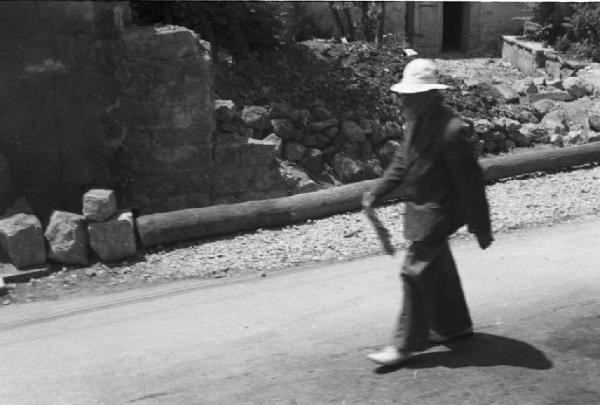 Viaggio in Jugoslavia. Dubrovnik (Ragusa): scene di vita quotidiana - uomo che cammina lungo una strada della città fiancheggiata da un muro semidistrutto