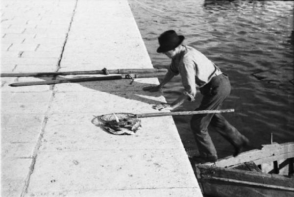 Viaggio in Jugoslavia. Gruz (Gravosa): pescatore risale dalla sua barca sulla banchina del porto