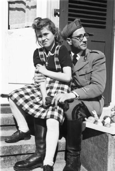 Internamento in Svizzera. Subingen. Famiglia di Don Mangili. Ritratto di coppia, adolescente seduta sulle ginocchia di un militare