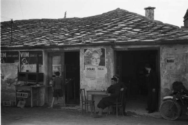 Viaggio in Jugoslavia. Mostar: scene di vita quotidiana - alcuni uomini seduti al tavolino di un bar lungo la strada