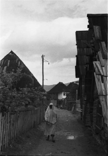 Viaggio in Jugoslavia. Yaitze: una donna bosniaca in costume locale in cammino tra le vie del villaggio