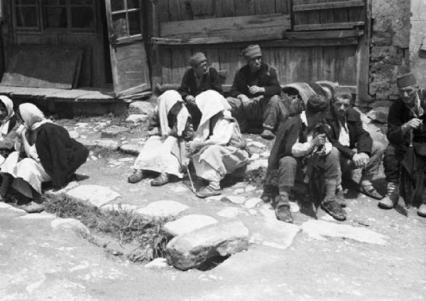 Viaggio in Jugoslavia. Yaitze: gruppi di persone in sosta al mercato seduti sopra un marciapiede