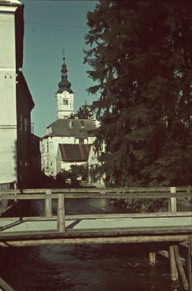 Viaggio in Jugoslavia. Zagabria: scorcio della città nei pressi di un piccolo fiumiciattolo - all'orizzonte si riconosce il campanile di una chiesa