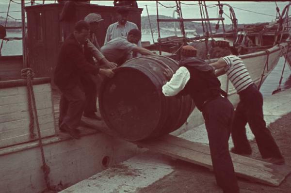 Viaggio in Jugoslavia. Sibenic (Sebenico): un gruppo di pescatori carica sulla barca una botte di legno in preparazione del viaggio