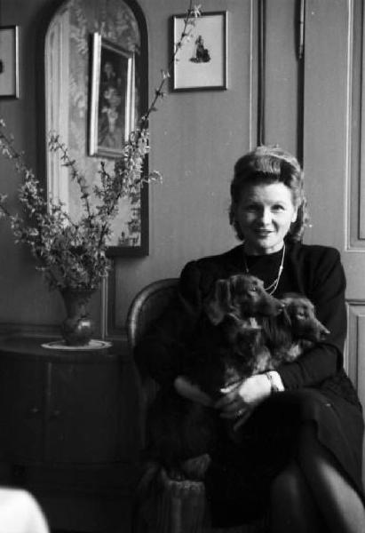 Internamento in Svizzera. Attisholz. Ritratto femminile, Milly nel soggiorno di casa con in braccio due cani bassotto