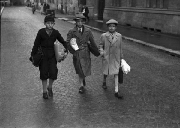 Italia seconda Guerra Mondiale. Milano - raccolta della lana durante il regime fascista: un gruppo di tre scolari in cammino verso la scuola con le buste piene di lana