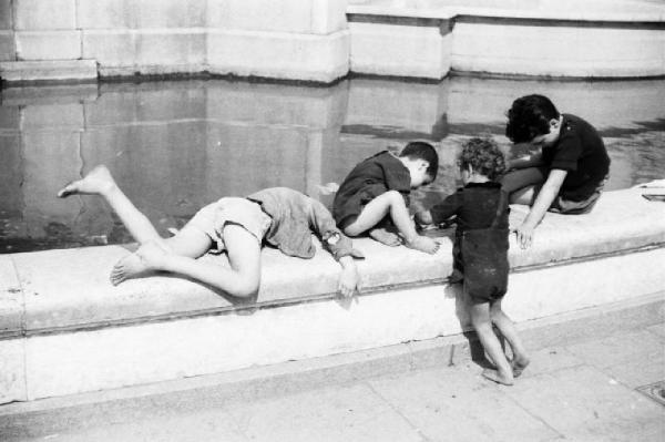 Roma - Alcuni bambini giocano sul bordo di una fontana