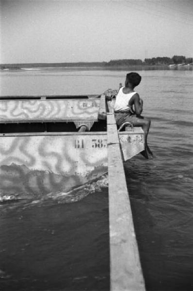Italia Dopoguerra. Tratto di fiume Po nei pressi di Cremona - Bambino seduto sul traghetto osserva il panorama