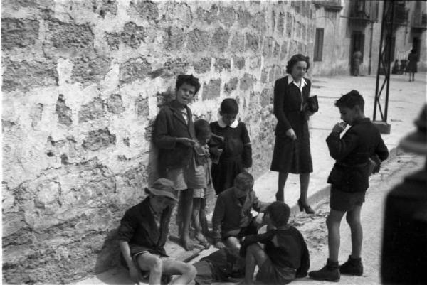 Palermo. Scolari e maestra sul ciglio della strada - alcuni seduti sul marciapiede