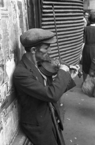 Italia Dopoguerra. Milano - Un uomo suona un violino per la strada
