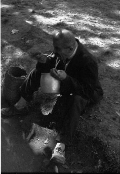 Italia Dopoguerra. Milano - Un uomo anziano seduto in un parco consuma il proprio pasto da un contenitore in alluminio