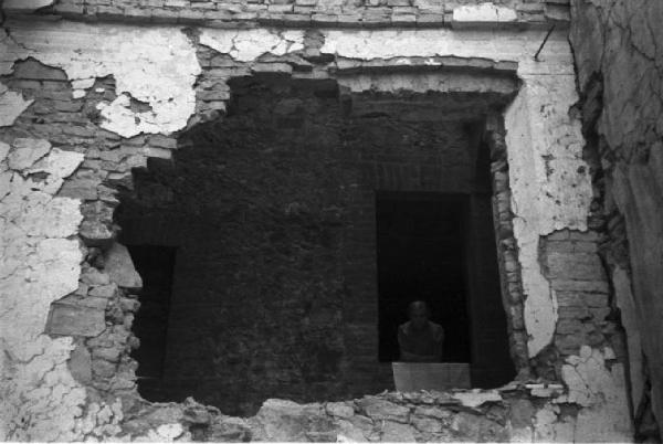 Italia Dopoguerra. Siena - Donna affacciata a una finestra vista attraverso uno squarcio dell'edificio adiacente