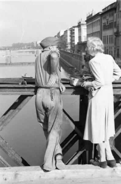 Italia Dopoguerra. Firenze - Un soldato chiacchera con una donna anziana appoggiato al parapetto del Victory Bridge