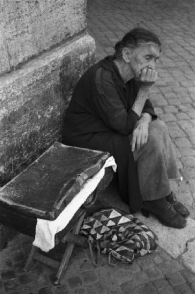 Italia Dopoguerra. Roma - Quartiere Trastevere - Anziana donna seduta all'angolo di una strada
