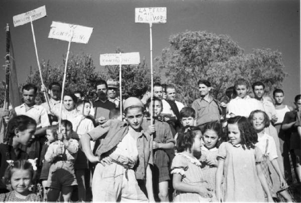 Invasione delle terre. Contadini che manifestano. I bambini in primo piano tengono in mano cartelli di protesta