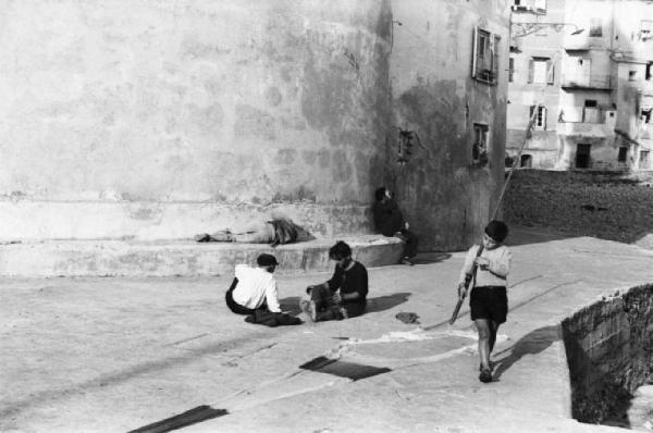 Italia Dopoguerra. Camogli - Scorcio del lungomare con coppia di pescatori alle prese con una rete e un bambino che passeggia