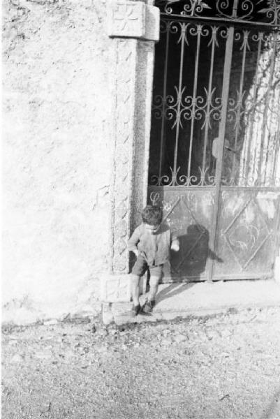 Bill e Pedro: ricostruzione dell'uccisione di Benito Mussolini. Dongo - Un fanciullo appoggiato al muro di cinta della sua abitazione durante la ricostruzione degli avvenimenti