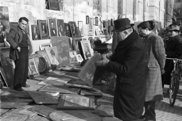 Italia Dopoguerra. Milano - fiera degli Obèi - Obèi: coppia di avventori presso un venditore di quadri