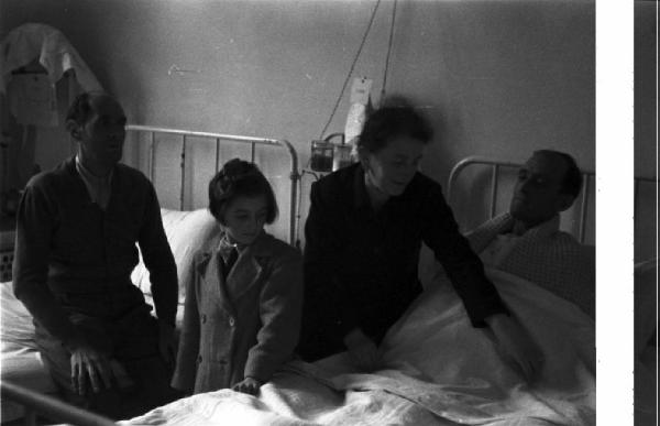 Italia Dopoguerra. Varese. Ospedale. Reparto maschile - una donna e una adolescente recano visita ai malati colpiti dal morbo giallo