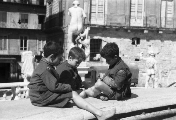 Italia Dopoguerra. Palermo. Tre bambini giocano seduti sul bordo della fontana Pretoria