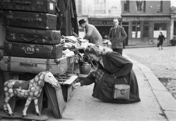 Parigi. Una donna guarda attentamente la merce di un ambulante robivecchi