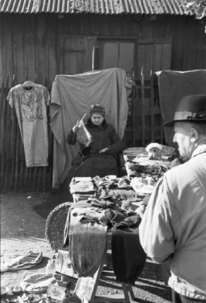 Le Vésinet. Il mercato delle pulci. Una donna vende abiti mentre lavora a maglia