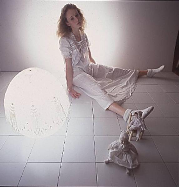 Donna con bambole e lampada tonda sdraiata sopra un pavimento