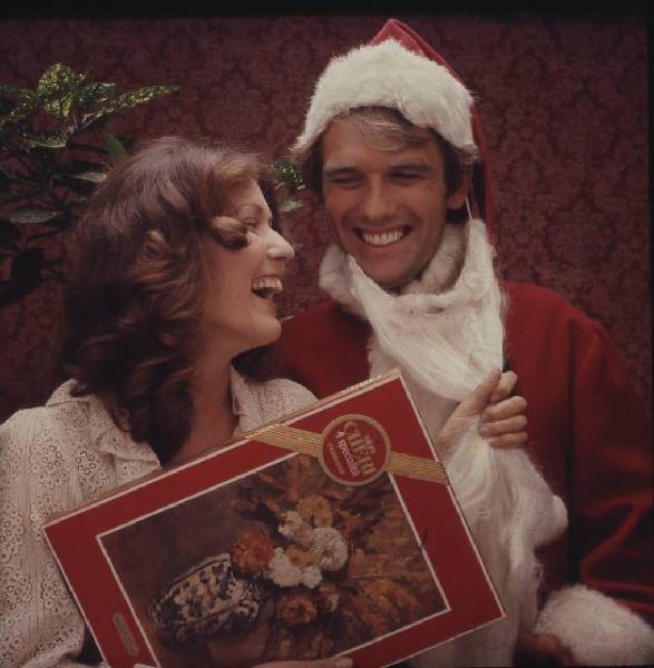 Campagna pubblicitaria Mon Cherì - uomo vesito da Babbo Natale e donna con una scatola di cioccolatini