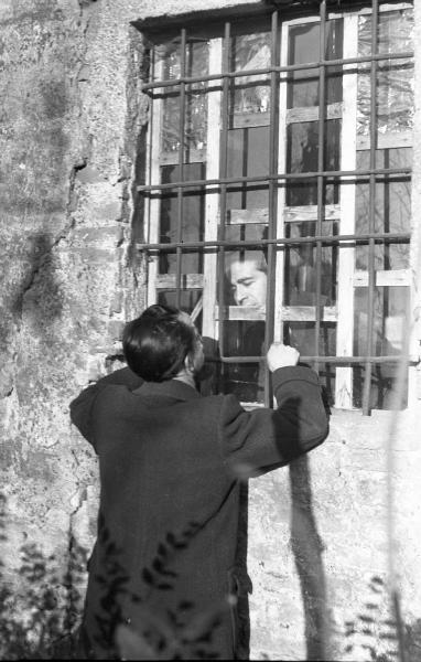 Due uomini parlano attraverso le sbarre di una finestra