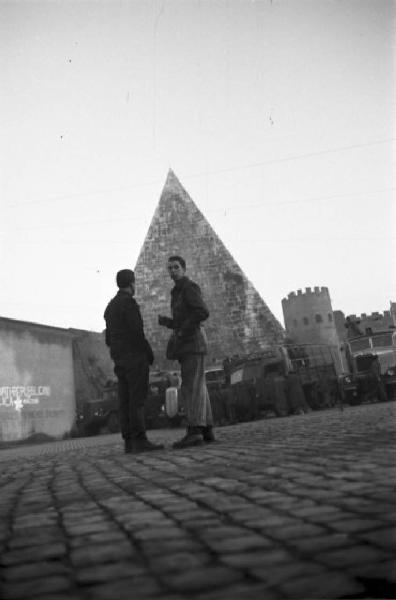 Italia Dopoguerra. Roma. Due uomini a colloquio davanti alla piramide di Caio Cestio e Porta San Paolo