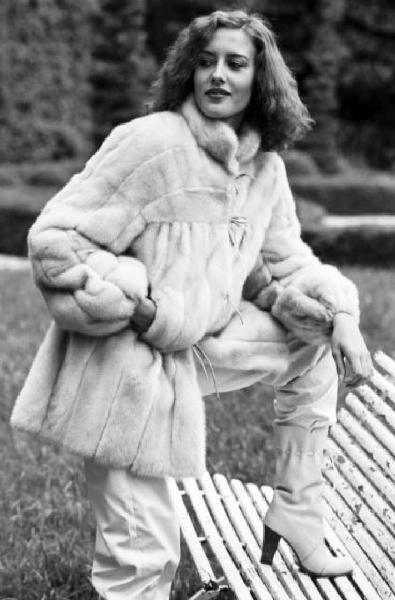 Fotomodella indossa una pelliccia di visone lavorata a pelle intera - Appoggia un piede su una panchina