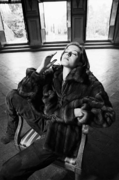 Fotomodella indossa una pelliccia di visone - giacca con coulisse in vita - Posa seduta nel salone di una villa