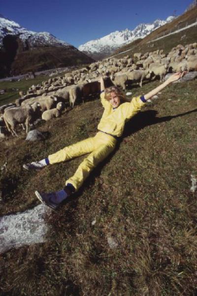 Campagna pubblicitaria Ellesse. Fotomodella indossa tuta da ginnastica gialla - prati di un alpeggio - gregge di pecore