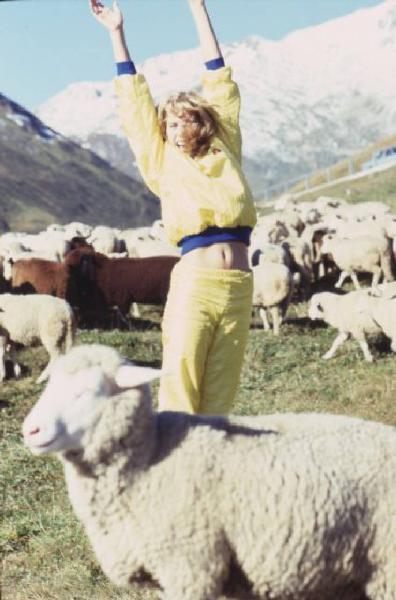 Campagna pubblicitaria Ellesse. Fotomodella indossa tuta da ginnastica gialla - prati di un alpeggio - gregge di pecore