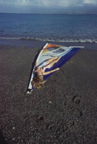 Campagna pubblicitaria Ellesse. Fotomodella indossa costume da bagno intero bianco -  vela di un windsurf