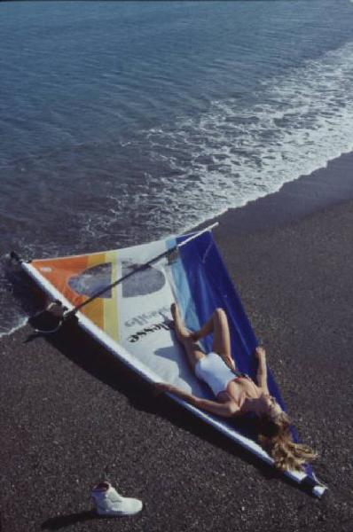 Campagna pubblicitaria Ellesse. Fotomodella indossa costume da bagno intero bianco - vela di un windsurf