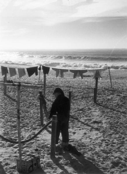 Nazaré. Pescatore stende le reti e biancheria appesa ad asciugare in spiaggia