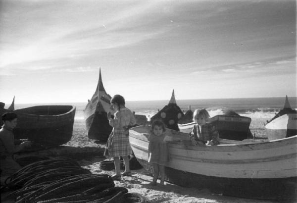 Nazaré - bambini tra le barche da pesca in secca sulla spiaggia