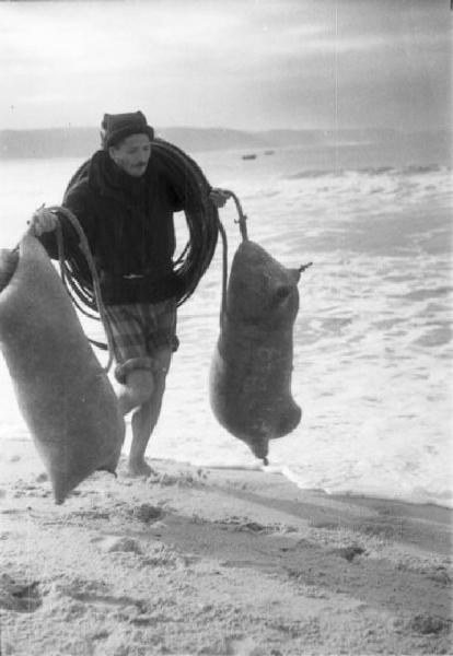 Spiaggia di Nazaré - pescatore raccoglie sacchi rigonfi utilizzati come galleggianti